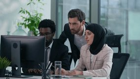 Multicultural business colleagues collaborating in modern office multiracial co-workers working African American male woman in hijab and Caucasian man looking at computer discussing teamwork startup - Powered by Shutterstock - Get 15% off with code: PIKWIZARD15