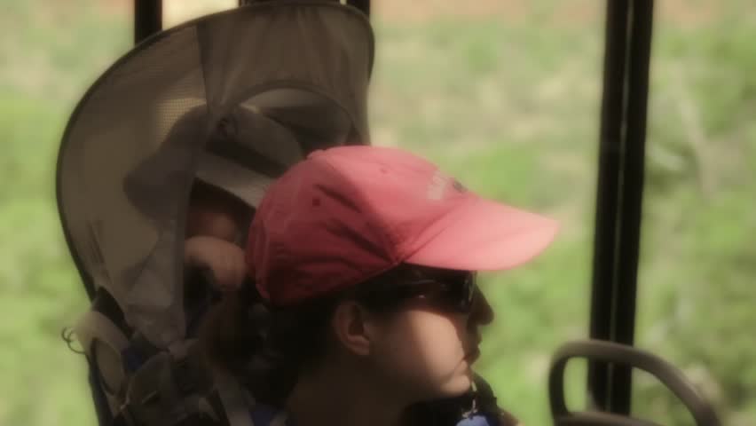 A mother and her baby boy in a carrier riding a shuttle through Zion National