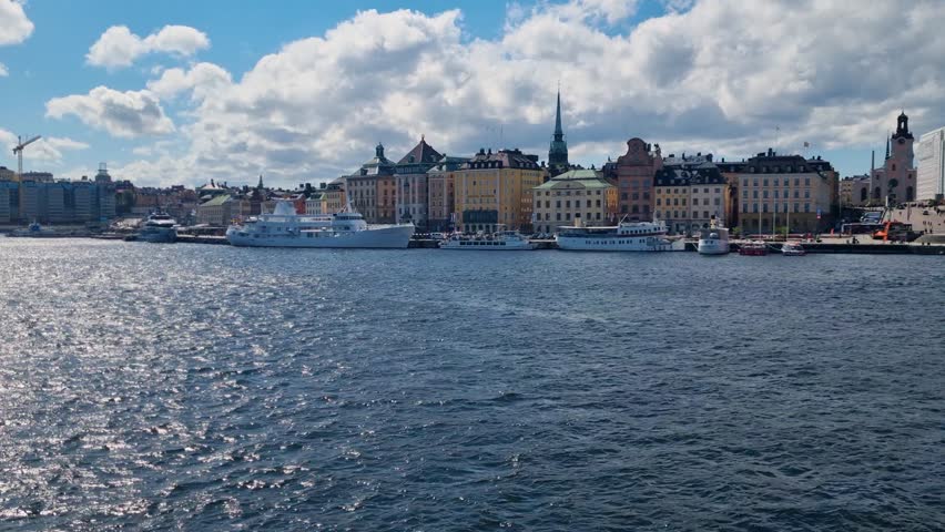View across Stockholms ström toward the Royal Palace in Stockholm, Sweden, showing boats on the water and the historic waterfront cityscape under clear, sunny skies