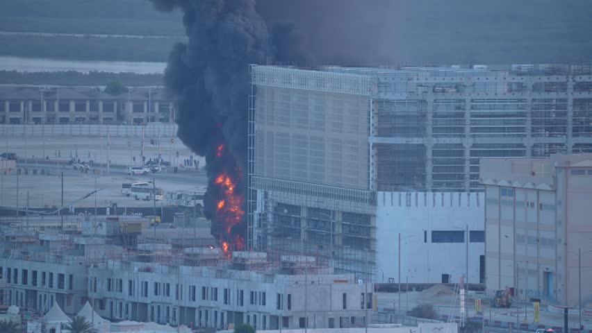 Dramatic footage captures a towering plume of black smoke and flames at an industrial construction site fire.