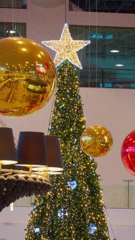 Festive Christmas decorations and giant tree at Palas Mall in Iasi, Romania during New Year holidays, featuring bright lights, shopping boutiques, and seasonal winter sale atmosphere inside.