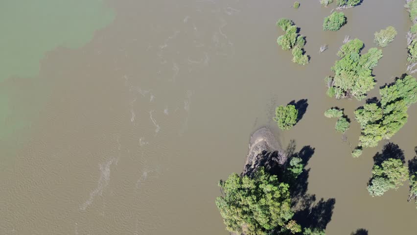 Camera panning up along the flow of the Confluence of the Vaal River and the Orange River. South of the town of Douglas, Northern Cape, South Africa. 4K Aerial Video.