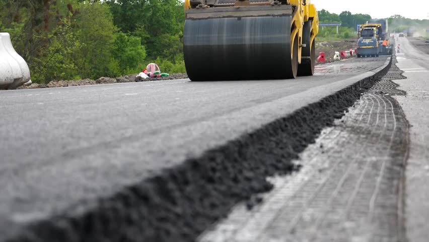 Roller laying new asphalt layer. Special machinery making road. Compactor constructing highway. Steamroller slowly ride. Roadway repair by heavy machinery. Concept of roadwork and motorway maintenance
