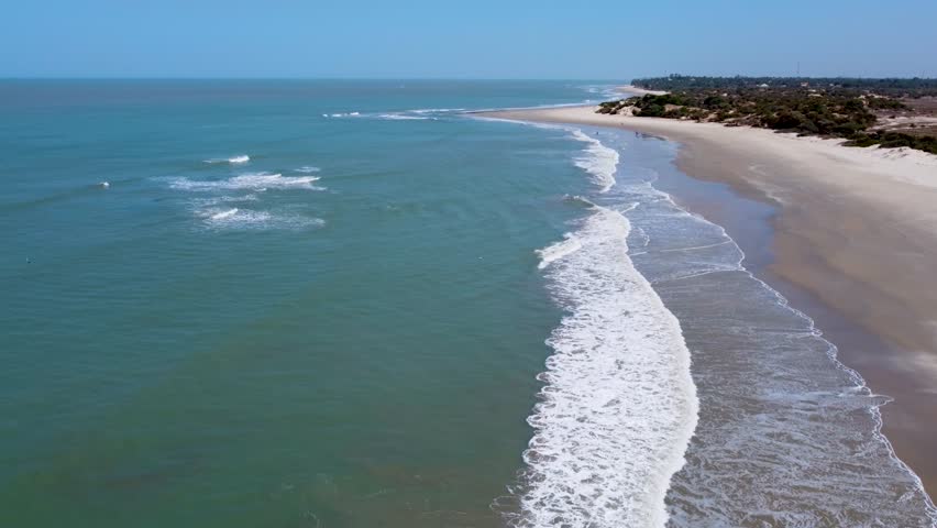 A long empty stretch of sandy beach at Cap Skirring, Senegal, with gentle Atlantic waves and bright tropical light along the shoreline.