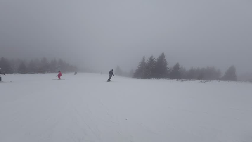Concept of bad weather and snow storm. A skier skis down a snowy slope in poor weather and visibility. First-person view