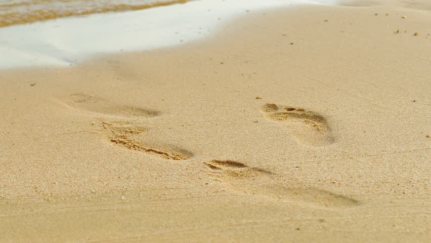 Human footprints on a sandy beach by the sea. A footprint in the sand. A tropical vacation, a tourist concept.