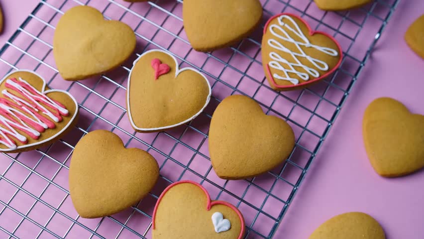 Delicious homemade heart shaped cookies with pink white icing on cooling rack for Valentine