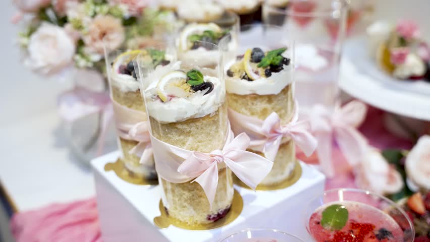 Individual cakes with cream, blueberries, and lemon slices decorating a dessert table for an event