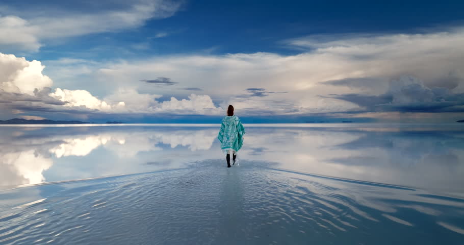 Female tourist wearing traditional Cholita shawl walking on Uyuni salt flat
