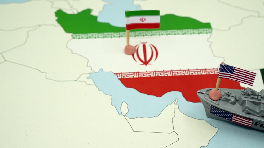 United States and Iran national flags on a geopolitical map with a toy warship, representing a potential military conflict or diplomatic tension between the two countries