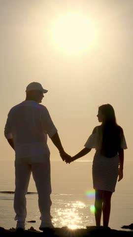 Couple silhouettes of people, Dad and daughter are admiring the sunrise over the sea. Summer morning. Dawn over the sea.