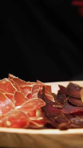 Meat appetizer. jamon. Delicious variety of meat appetizers, Prosciutto crudo or jamon meat with rosemary on serving wooden platter. The chef puts jamon on serving board.
