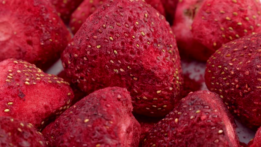 Red whole freeze dried strawberry berries circle rotation close up