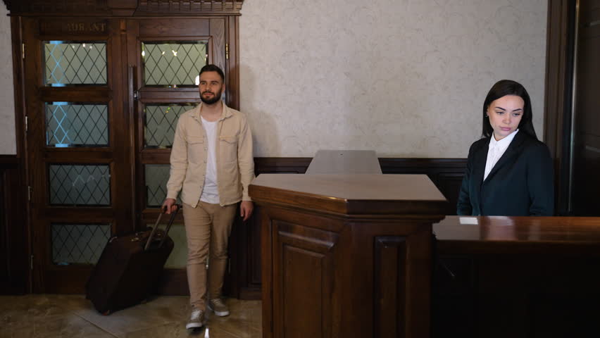 Male guest with luggage arriving at hotel reception desk