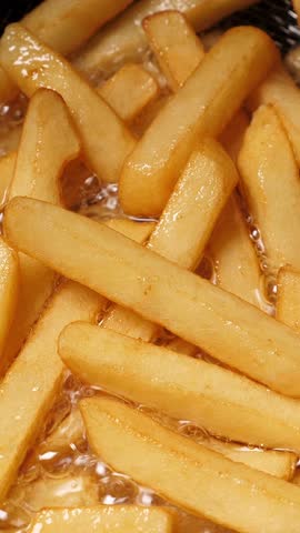 Cooking french fries potatoes in deep fryer. Closeup. Vertical footage