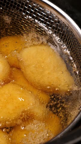 Cooking tempura chicken nuggets in deep fryer. Closeup. Vertical footage
