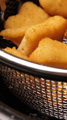 Cooking tempura chicken nuggets in deep fryer. Closeup. Vertical footage