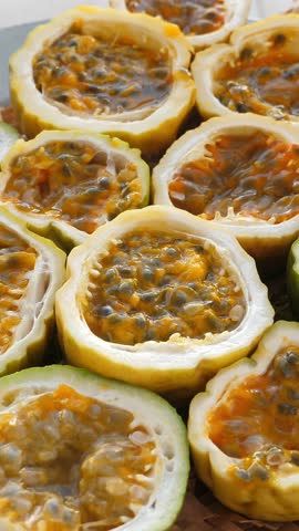 Passion fruit background with half cut chinola. A lot of sliced maracuja. Tropical fruits backdrop. Vertical footage
