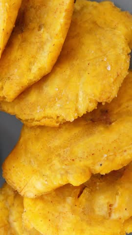 Fried platanos on plate. Sliced and cooked tostones. Rotating. Vertical footage