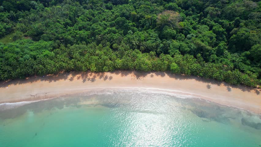 Aerial view of the sun shining on the turquoise sea at Bom Bom beach with the inscription Prince Island in the sand. Prince Island,Sao Tome,Africa