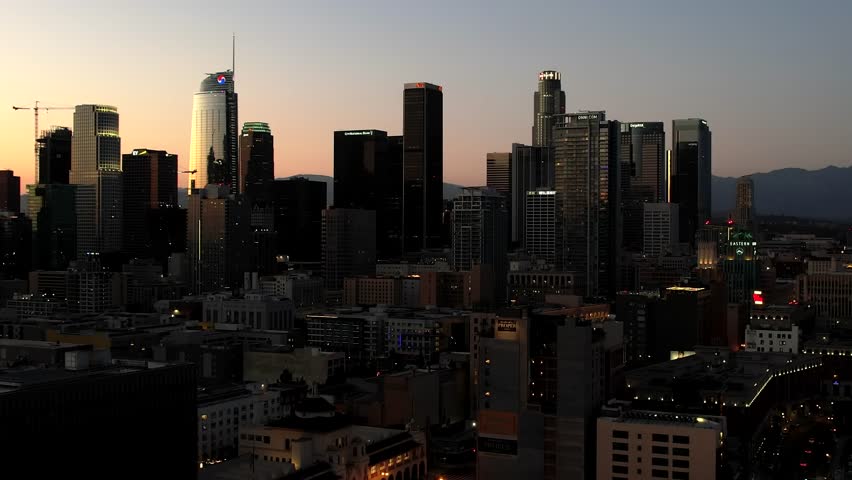 Establishing Aerial view of Downtown Los Angeles skyline at sunset, skyscrapers against a colorful sky during golden hour, an iconic urban cityscape in California