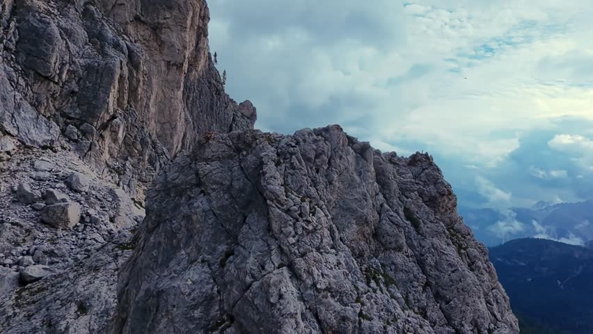 Dolomies, Italy Rocky Summit Ridge In Dolomites, Aerial Panorama Showing Jagged Rock Face And Distant Peaks, Mountain Guide Scouting Route Under Brooding Clouds, Dramatic Light And Textured