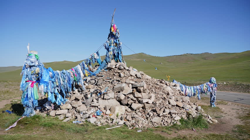 Sacred Ovoo Cairn with Prayer Flags on Mongolian Steppe Under Blue Sky