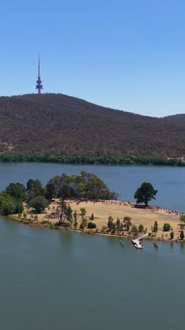 Static wide shot of a telecommunications tower atop a hill overlooking a calm lake