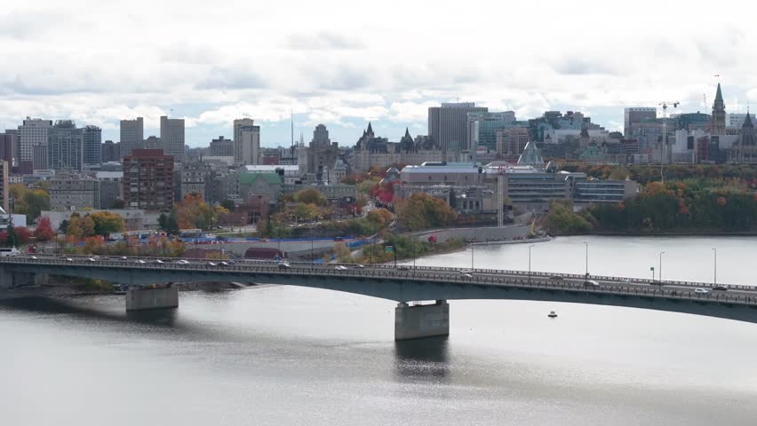 Beautiful aerial view of the Ottawa skyline, Parliament Hill, and Alexandra Bridge surrounded by colorful autumn foliage.