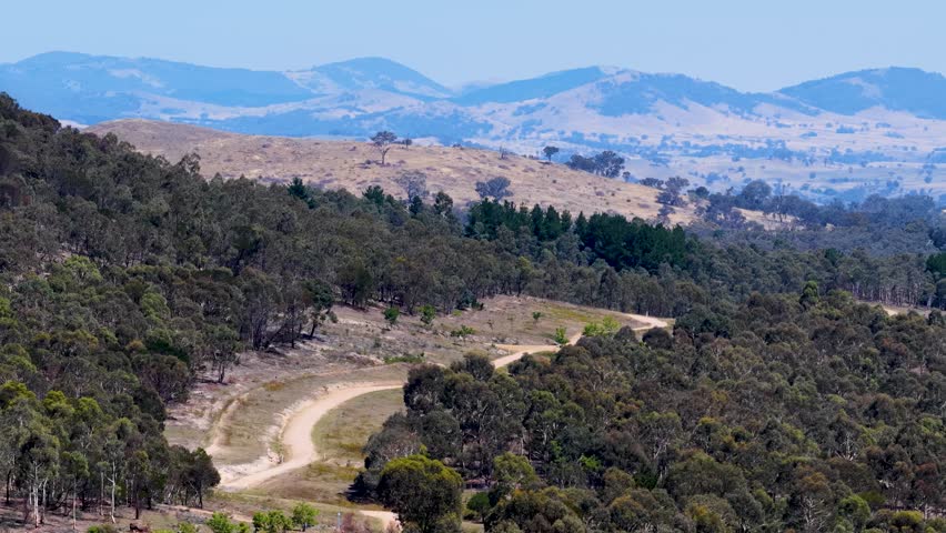 High angle drone shot of a dirt mountain bike trail winding through Australian bushland
