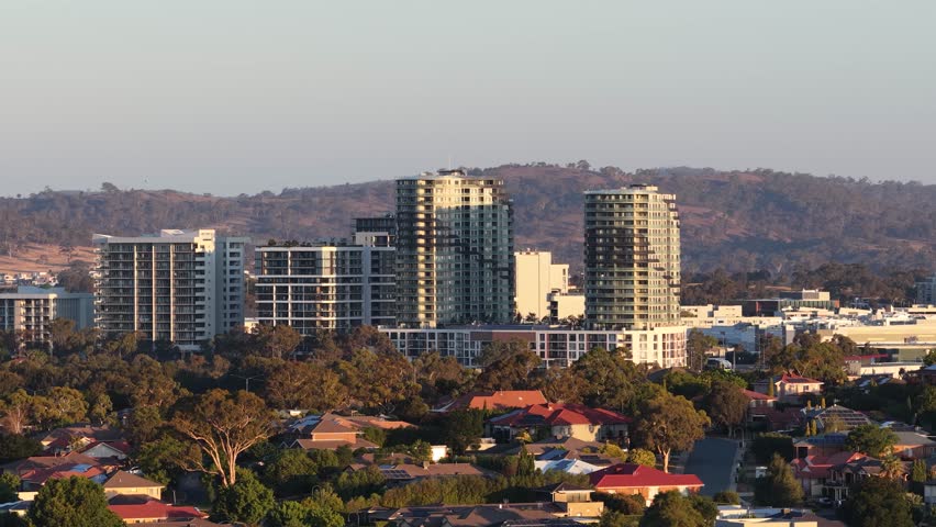 Wide static shot of high-rise apartment buildings and residential houses under warm afternoon sunlight