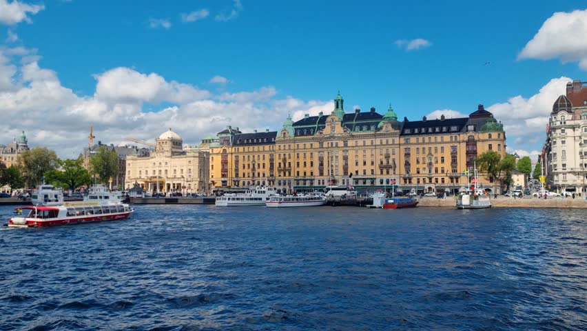 View of Stockholms ström along the Strandvägen promenade and Nybroviken bay in Stockholm, Sweden, on a sunny day, featuring historic waterfront buildings, boats, and vibrant city life