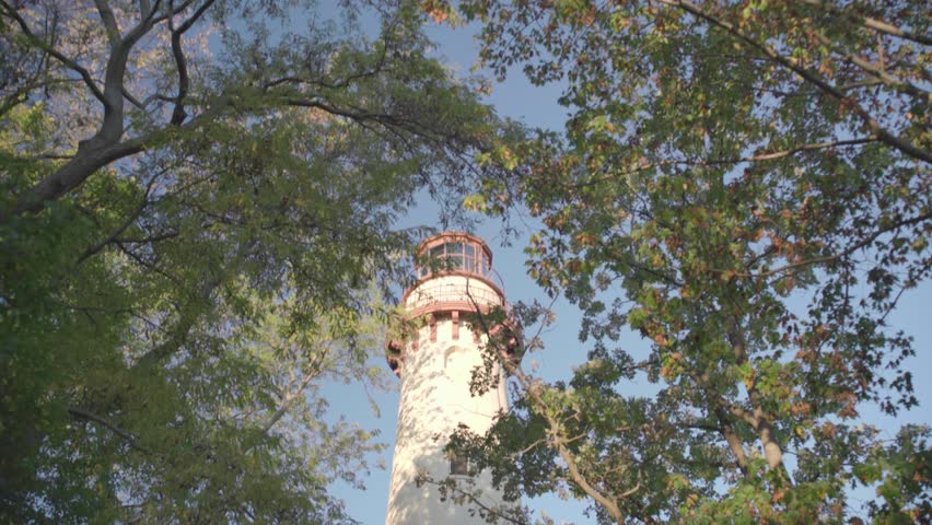 Grosse Point Lighthouse framed by leafy trees in early autumn.