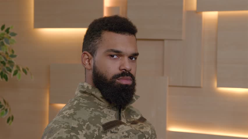 Portrait of serious good looking bearded African American male army soldier in military uniform posing indoors, expressing confidence , determination and pride