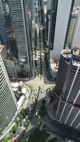 Stunning vertical slow-motion aerial perspective gradually tilting downward to reveal the bustling roads of Makati business district in Manila, Philippines. This dramatic bird