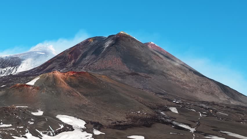 Mount Etna slopes with hardened lava flows and melting snow, aerial tracking left, Sicily Italy