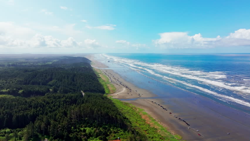 Aerial drone view of Seabrook, Washington, showing beach, Pacific Ocean waves, and coastal shoreline. Dynamic seaside scenery ideal for travel, nature, and ocean footage.