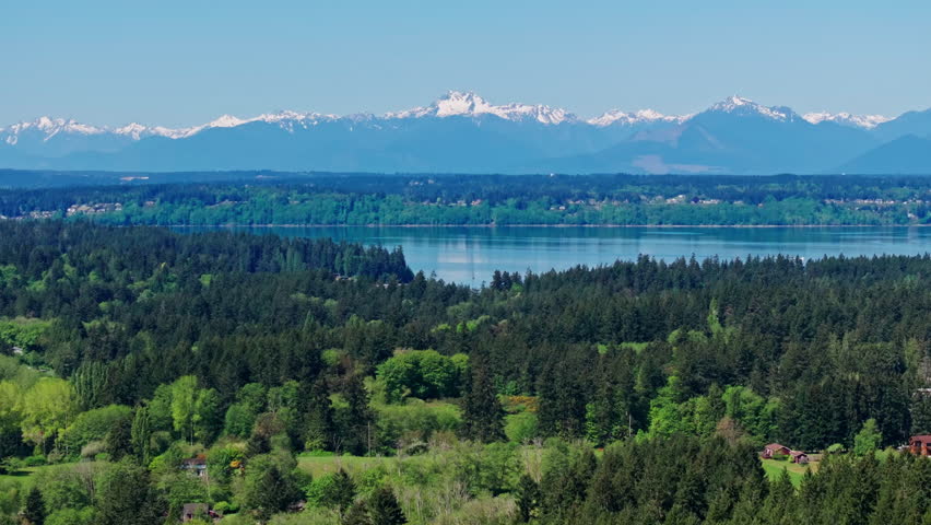 Aerial drone view of Olympic National Park, Seattle, Washington, showcasing a pristine mountain lake surrounded by forest and alpine peaks. Serene, natural landscape.