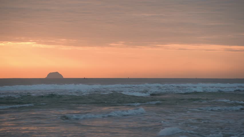 Morning sunrise over the ocean with islands and small boats in the background