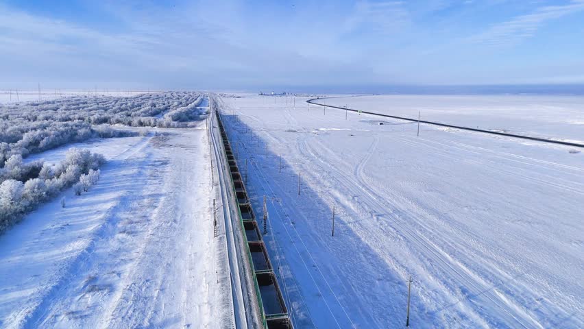 a train with empty carriages is traveling on a winter railway, with trees covered in white frost