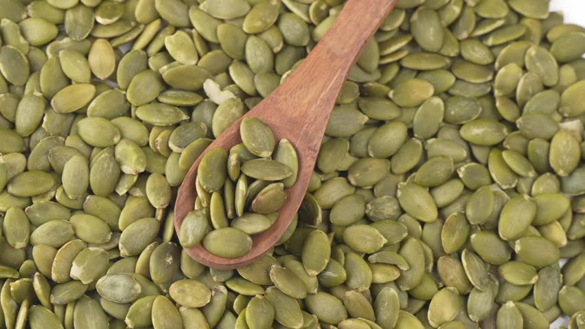 Green fresh Pumpkin seeds on a spoon.