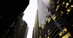 Looking up at towering skyscrapers during dusk, with their glass facades reflecting the low light. The buildings rise sharply against a cloudy sky, creating a striking urban atmosphere. - Powered by Shutterstock - Get 15% off with code: PIKWIZARD15