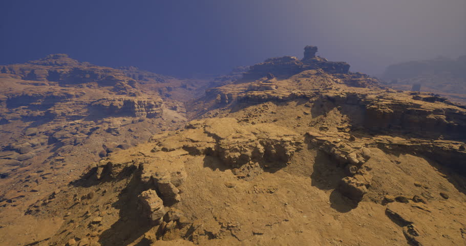 The rocky terrain features rugged cliffs and sandy surfaces under a clear sky. The serene atmosphere captures the beauty of the desert landscape during a tranquil afternoon.