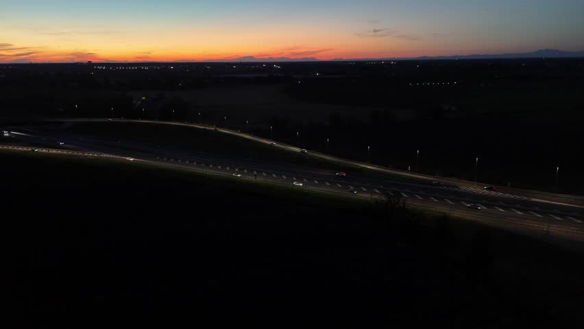 Night shot of the A1 and A21 motorway interchange near Piacenza, Italy, featuring twilight skies and regional traffic flow.