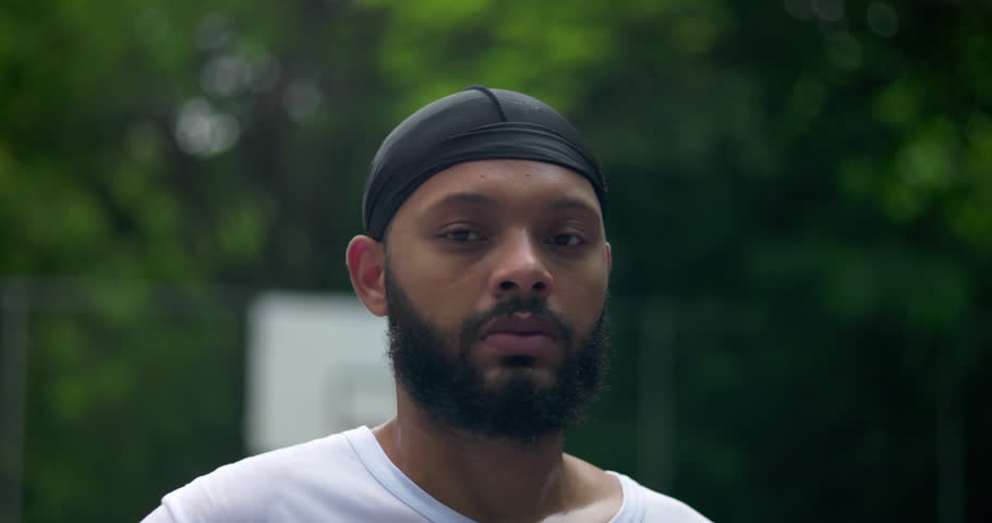 African American man portrait on basketball court, serious and composed expression representing discipline, confidence, and mental strength in urban athletic life