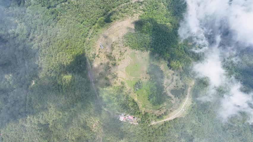 Drone eye over Wolobobo crater. Shadows dance across the serene lake, encircled by misty forests and earthen paths in Indonesia hidden gem