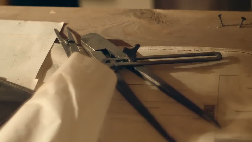 In the twilight, the table of an ancient archaeologist, explorer, adventurer hunter on which a plans, a caliper on the table. Sepia tone. Shot in motion. Closeup