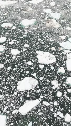 Polar spring icebergs frame solitary sailing yacht near Greenland mountains