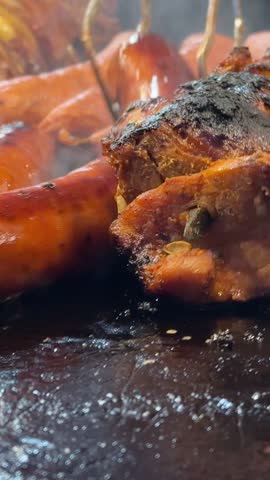 Juicy sausages sizzling on grill with smoke and flames in dark barbecue atmosphere