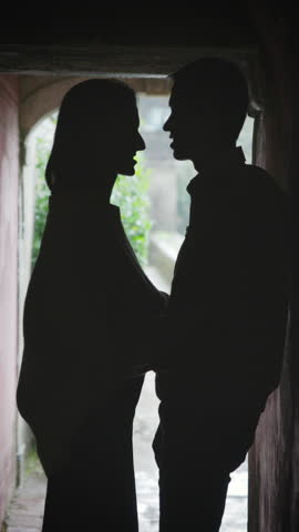 Silhouette of romantic couple kissing in dark alleyway